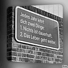 a black and white photo of a sign on a brick wall