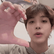 a young man is making a heart shape with his hands