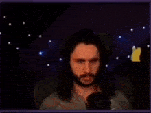 a man with a beard is sitting in front of a microphone