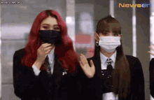 two girls wearing face masks and suits are standing next to each other .