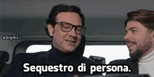 two men are sitting in a car and one of them is wearing glasses and the caption says sequestro di persona