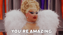 a drag queen says you 're amazing in a white feathered outfit