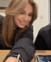 a woman is smiling while sitting at a table with a phone .