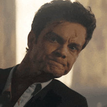 a man with blood on his face is wearing a suit