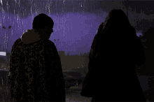 a man in a robe stands in the rain with a purple sky in the background