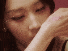 a close up of a woman 's face with glitter on her hand