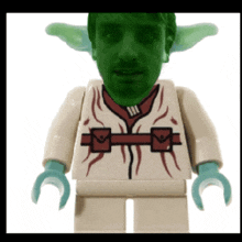 a lego figure with a green face and green ears is wearing a white shirt
