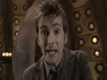 a man in a suit and tie is making a funny face in front of a wall .