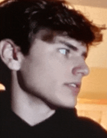 a close up of a young man 's face with a black shirt