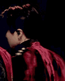 a close up of a person wearing a red jacket and a black shirt .