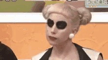 a woman with blonde hair and black eyes is wearing a black and white outfit .