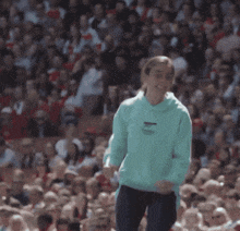 a man in a green hoodie stands in front of a crowd of people