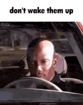 a bald man is driving a car with the words " don 't wake them up " on the bottom