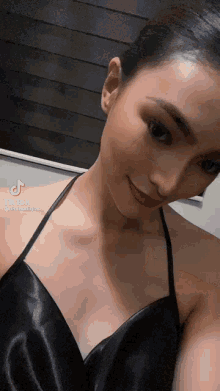 a woman in a black dress is smiling and looking at the camera
