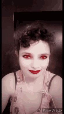 a woman with red eyes is wearing ear buds and a pink tank top