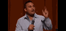 a man is holding a microphone and making a funny face while standing on a stage .