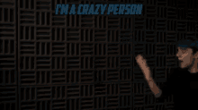 a man with blue hair is standing in front of a wall with the words i 'm a crazy person written on it