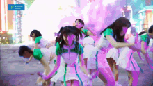 a group of girls are dancing in front of a blue sign that says upfront working