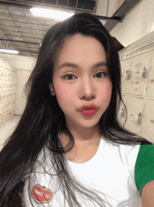 a woman wearing a white shirt with a tomato on it takes a selfie