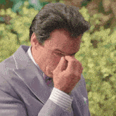 a man in a suit and bow tie wipes his nose