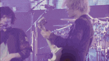 a man playing a guitar in front of a microphone with the letter d in the corner