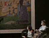a woman in a wheelchair sits next to a man looking at a painting
