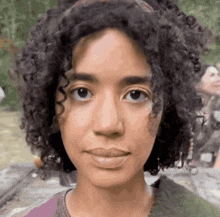 a woman with curly hair looks at the camera with a smile on her face