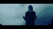 a woman in a black jacket is standing in a dark room with her hands outstretched