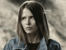 a woman in a denim jacket is making a funny face .