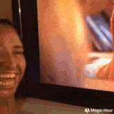 a woman is smiling in front of a tv screen that says magic hour on it