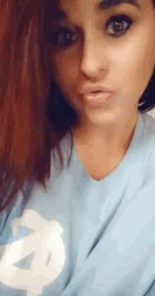 a woman wearing a light blue shirt with a white letter a on it
