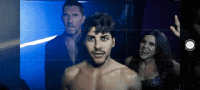 a man without a shirt is surrounded by two other men
