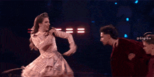 a woman in a gold dress touches the head of a man