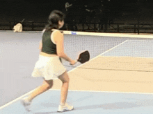 a woman is holding a tennis racket on a tennis court
