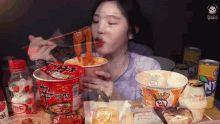 a woman is eating noodles from a red cup with the word ramen on it