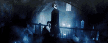 a man in a black robe is standing in a dark room with a blue light behind him .