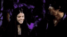 a man and a woman are standing next to each other in the dark .