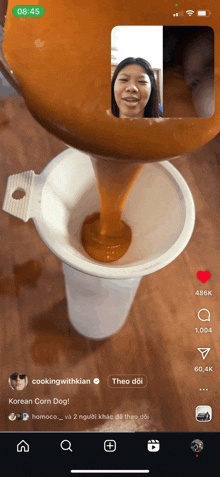 a phone screen shows a video of a woman pouring sauce into a cone