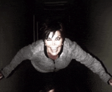 a woman is standing in a dark room with her arms outstretched and smiling .