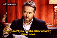 a man with a beard is sitting at a table with chopsticks in his hand and a red curtain behind him .