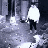 a black and white photo of a man holding a flashlight in a room with chairs and a sign that says fire police