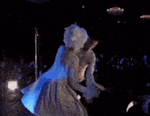 a woman in a white dress is dancing on a stage in front of a sign that says sonic