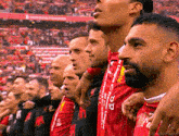 a group of men are standing in a stadium wearing red and black striped jerseys with the letter a on them
