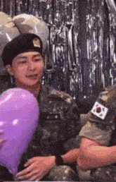 a man in a military uniform is sitting next to a woman holding a heart shaped balloon .