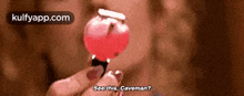 a woman is holding a red lollipop in her hand .