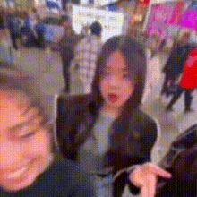 a blurry picture of two women standing next to each other in a crowded area .