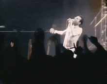 a man singing into a microphone in front of a crowd of people