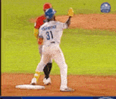 a baseball player with the number 31 on his back is throwing a baseball