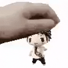 a hand is holding a small figurine of a man in a tie on top of his head .