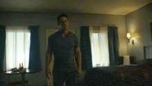 a man standing in a hotel room with a bottle of beer on the table